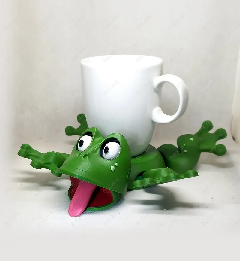 Green frog-shaped cup holder with raised eyes, open mouth, tongue, and splayed legs